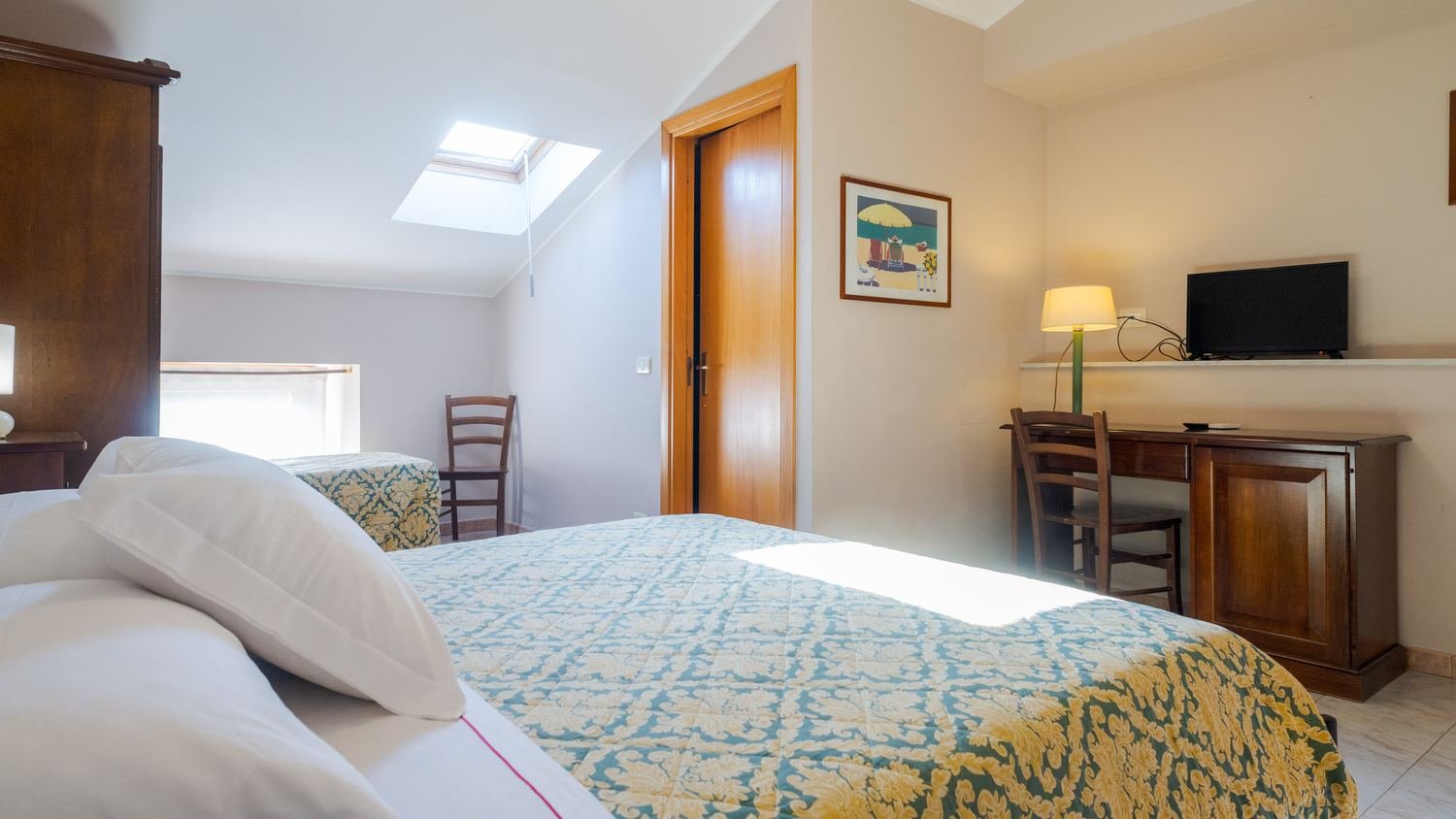 Camera mansardata con lucernario e letto matrimoniale