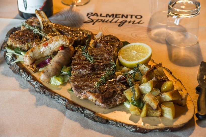 Grigliata mista di carne servita su ardesia con patate