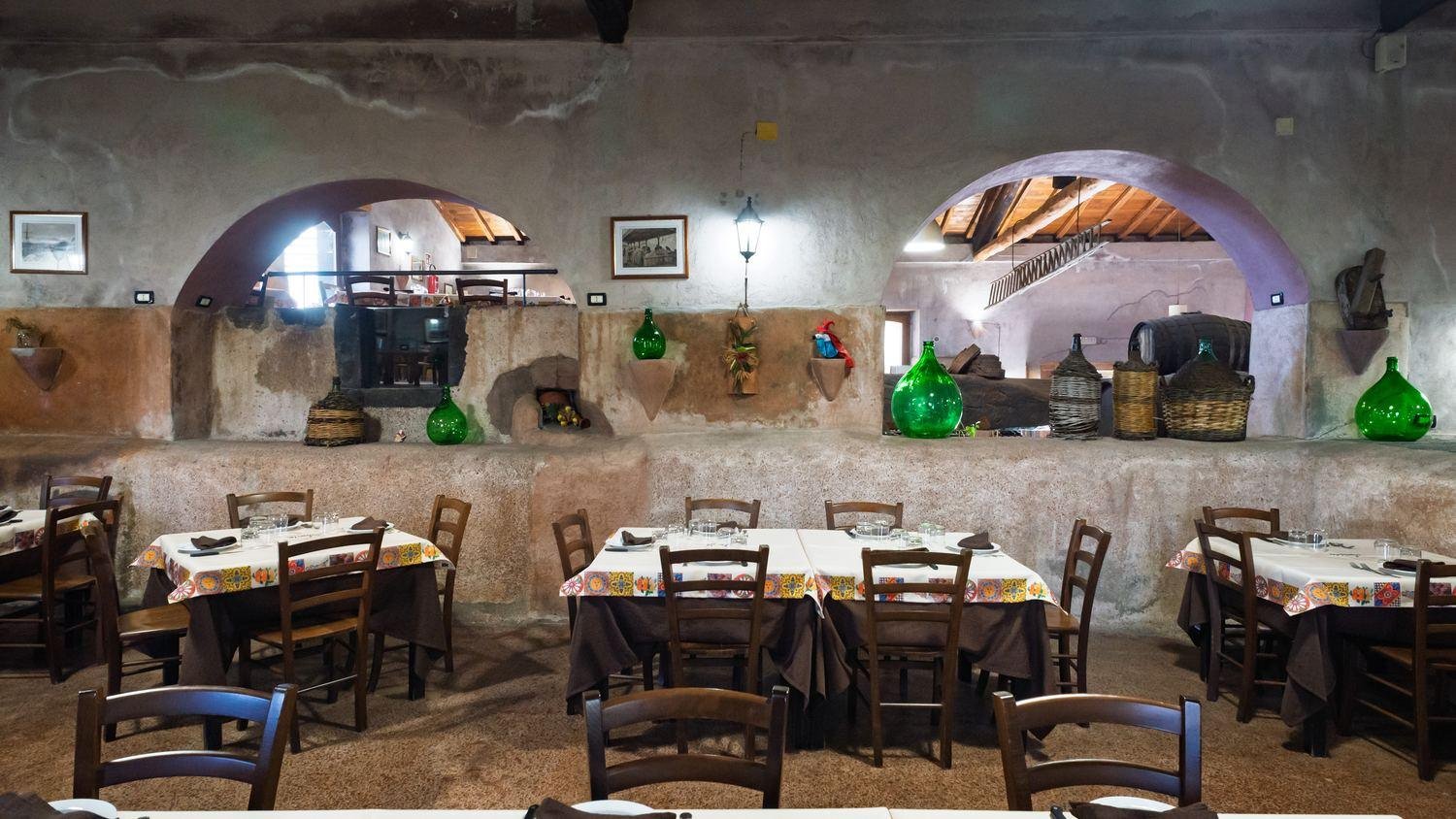 La sala del palmento con gli archi in pietra e le damigiane