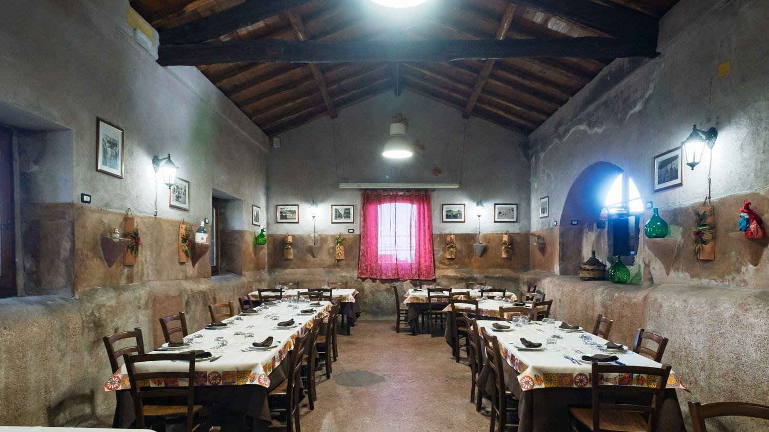 Sala rustica con tavoli apparecchiati sotto le travi